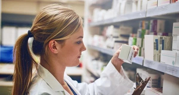 Apothekerin-liest-Text-auf-Medikamentenverpackung