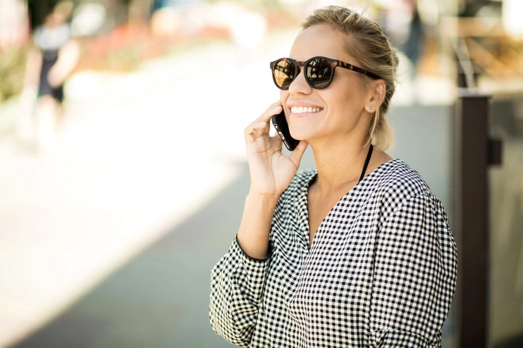 Junge blonde Frau telefoniert draußen mit ihrem Handy