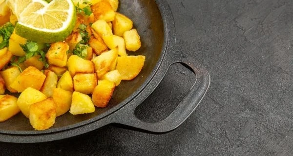 front-view-tasty-fried-potatoes-inside-pan-with-lemon-slices-dark-table