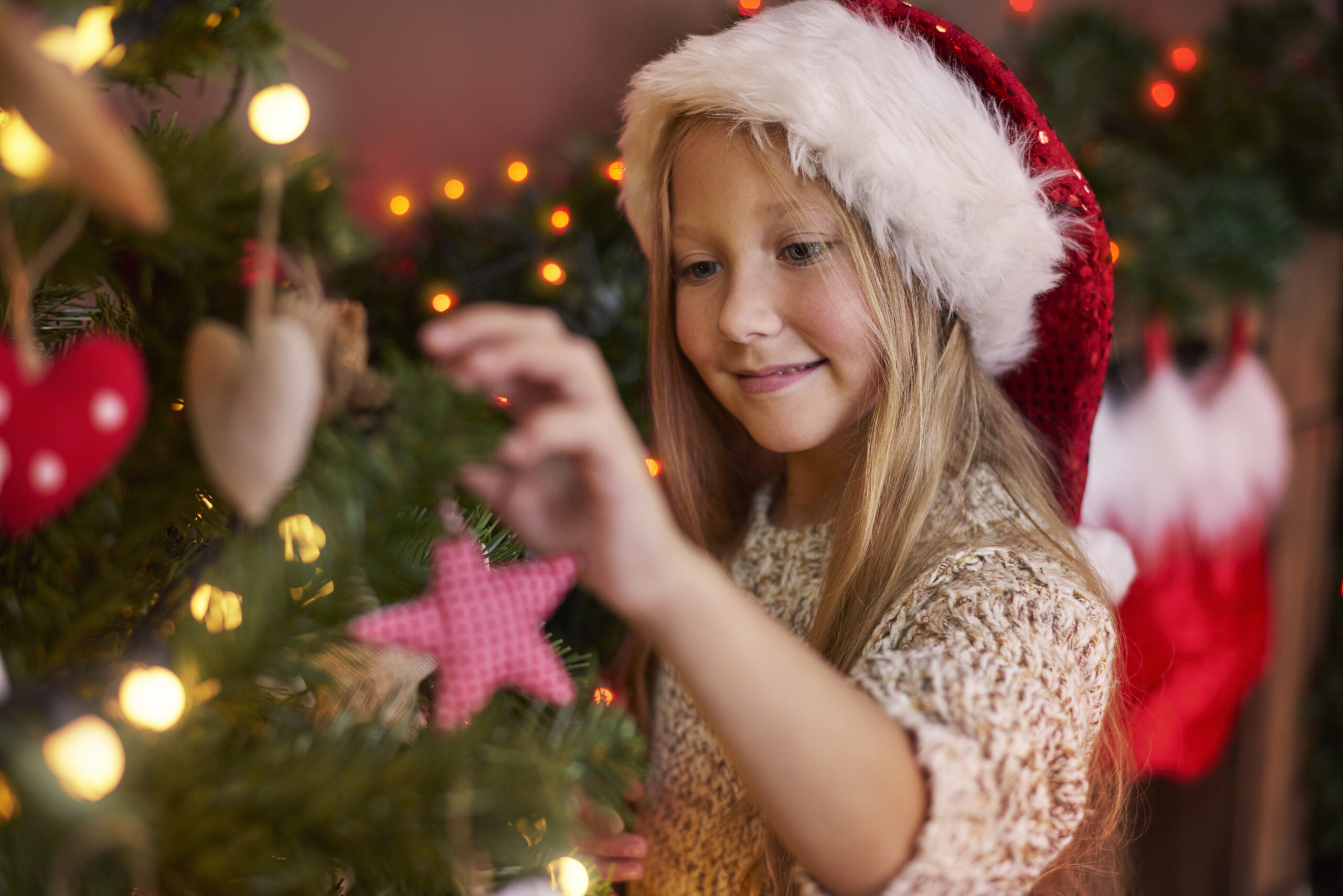 Ein kleines Mädchen hängt Schmuck an einen Weihnachtsbaum