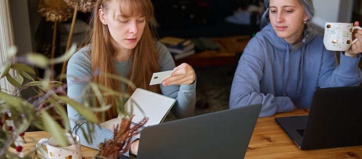 Zwei Frauen sitzen vor ihren Laptops und bestellen online