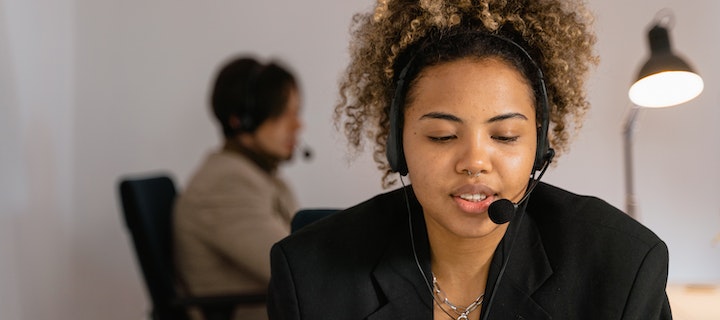 Frau in schwarzem Blaser mit Headset