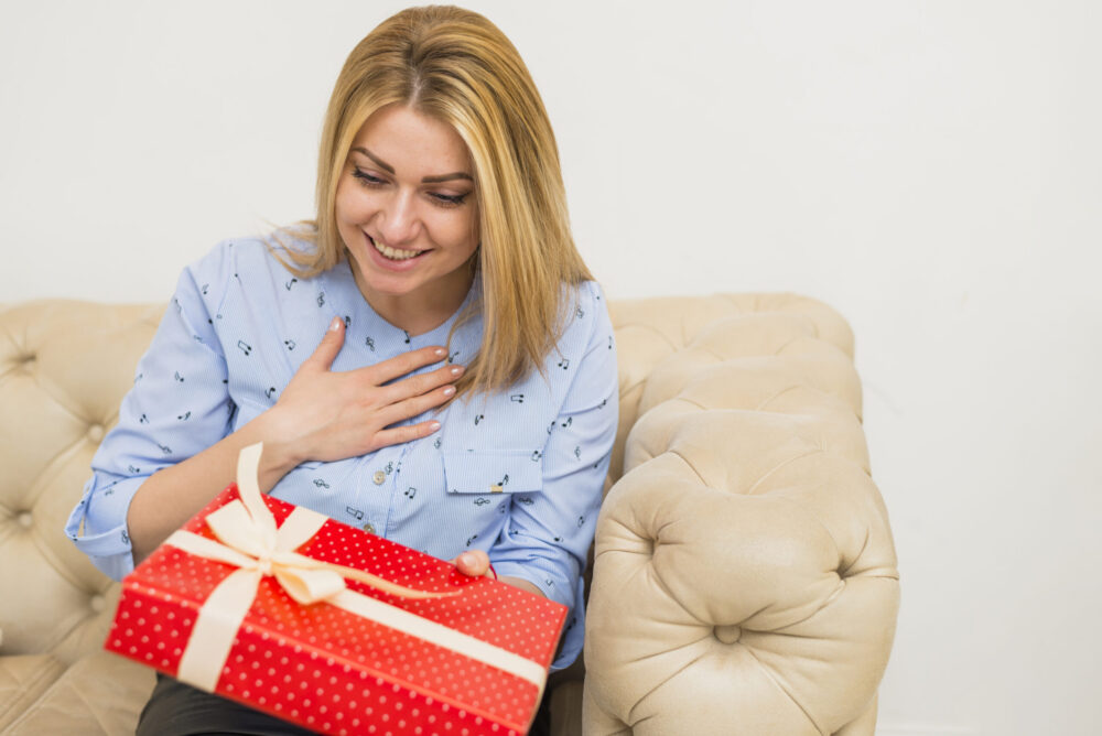 Eine Frau ist überrascht und glücklich, sie hält ein Geschenk in der Hand